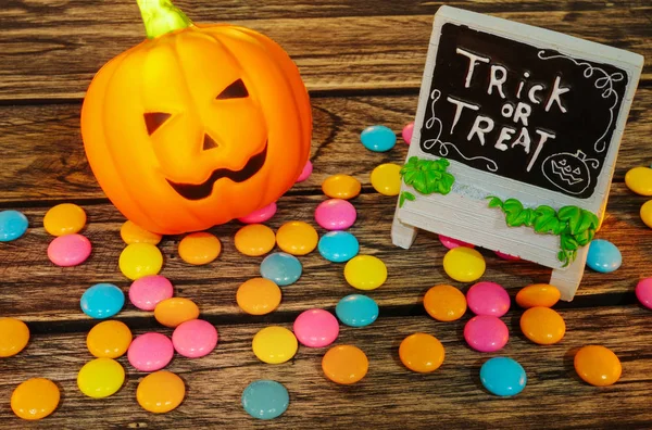 Halloween décoration tour ou régal, citrouille Jack-o-lanterne avec des bonbons sur fond en bois — Photo