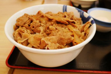 Gyudon kase dilimlenmiş biftek, soğan ve tatlı sos ile tepesinde pirinç kadar kapatın.