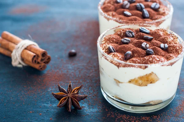 Tiramisu em um copo decorado com grãos de café em um fundo escuro — Fotografia de Stock