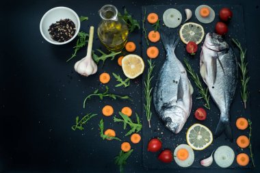 Taze çiğ çiğ dorado balık limonlu, otlar, petrol, sebze ve baharat siyah zemin üzerinde görünümü top