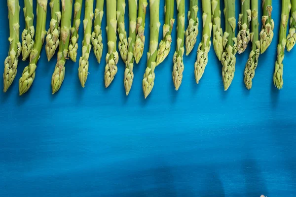 Fresh green asparagus shoots pattern, on a blue wooden background top view — Stock Photo, Image