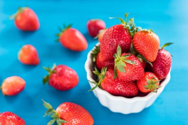 Olgun kırmızı çilek Çilek beyaz kase taze çilek, mavi ahşap masada.