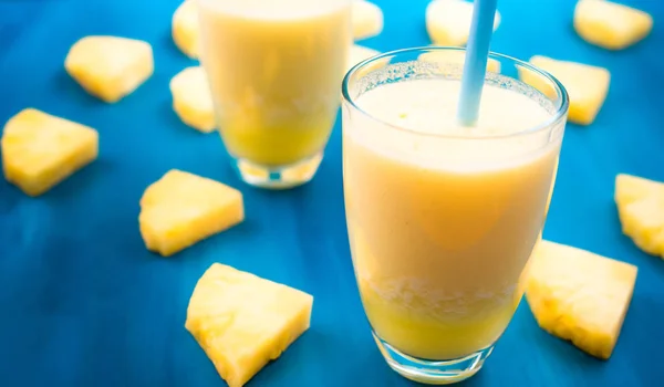 Batido de piña con piña fresca sobre mesa azul madera . — Foto de Stock