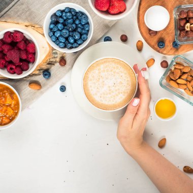 Günaydın - yulaf ezmesi kahve, çilek, yumurta, fındık ile sağlıklı kahvaltı arka plan. Kahve, eller, tutun, cup. Beyaz ahşap gıda arka plan, üstten görünüm