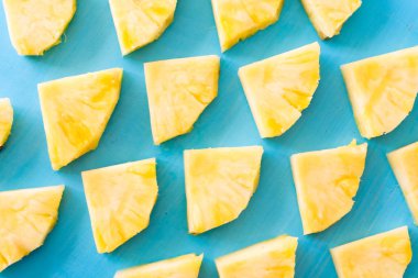 Bahar ya da yaz konsepti: bilmece birçok mavi ahşap masa arka plan üzerinde döşeme sarı ananas parçaları kadar yakın.