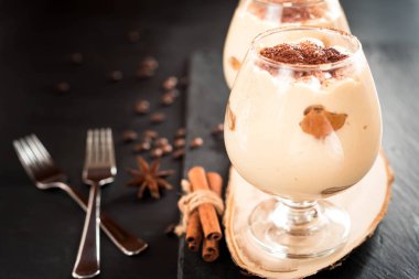 karanlık bir arka plan üzerinde kahve çekirdekleri ile dekore edilmiş bir cam tiramisu