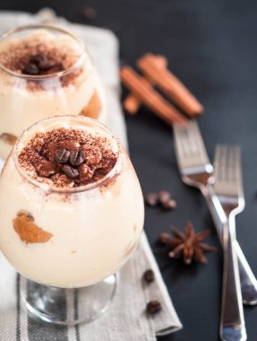 karanlık bir arka plan üzerinde kahve çekirdekleri ile dekore edilmiş bir cam tiramisu