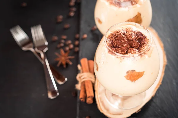 Tiramisu in een glaasje versierd met koffiebonen op een donkere achtergrond — Stockfoto