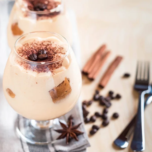 Lekkere tiramisu dessert in glas, op servet, op houten achtergrond — Stockfoto