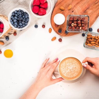 Günaydın - yulaf ezmesi kahve, çilek, yumurta, fındık ile sağlıklı kahvaltı arka plan. Kahve, eller, tutun, cup. Beyaz ahşap gıda arka plan, üstten görünüm