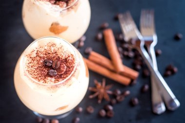 karanlık bir arka plan üzerinde kahve çekirdekleri ile dekore edilmiş bir cam tiramisu