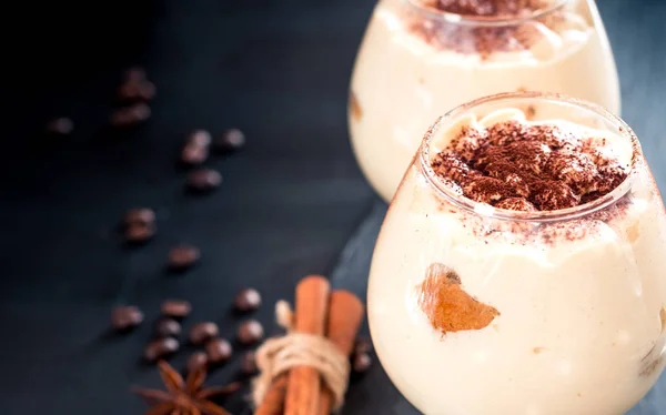 Tiramisu in een glaasje versierd met koffiebonen op een donkere achtergrond, ruimte voor tekst — Stockfoto