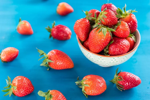 Olgun kırmızı çilek Çilek beyaz kase taze çilek, mavi ahşap masada.
