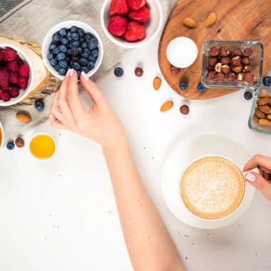 Günaydın - yulaf ezmesi kahve, çilek, yumurta, fındık ile sağlıklı kahvaltı arka plan. Kahve, eller, tutun, cup. Beyaz ahşap gıda arka plan, üstten görünüm