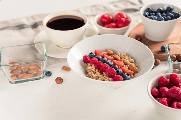 Dzień dobry - tło zdrowy śniadanie z kawy płatki owsiane, jagody, jaja, orzechy. Biały drewniany jedzenie, — Zdjęcie stockowe