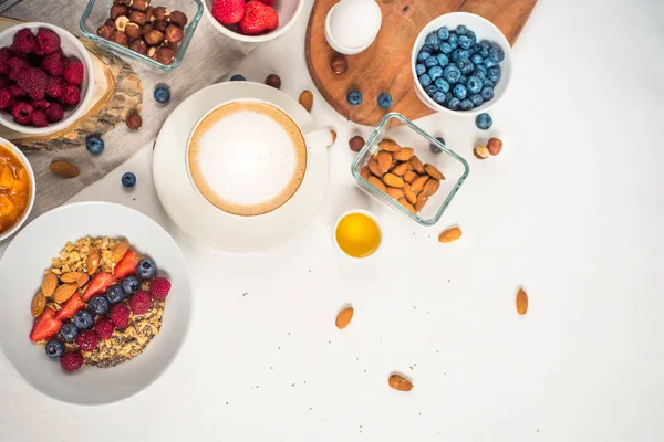 Доброе утро - здоровый завтрак с овсянкой кофе, ягодами, яйцом, орехами. Белый деревянный пищевой фон, вид сверху — стоковое фото
