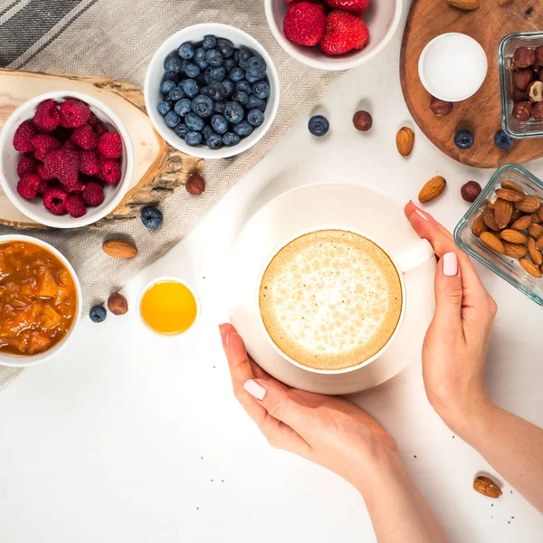 Günaydın - yulaf ezmesi kahve, çilek, yumurta, fındık ile sağlıklı kahvaltı arka plan. Kahve, eller, tutun, cup. Beyaz ahşap gıda arka plan, üstten görünüm