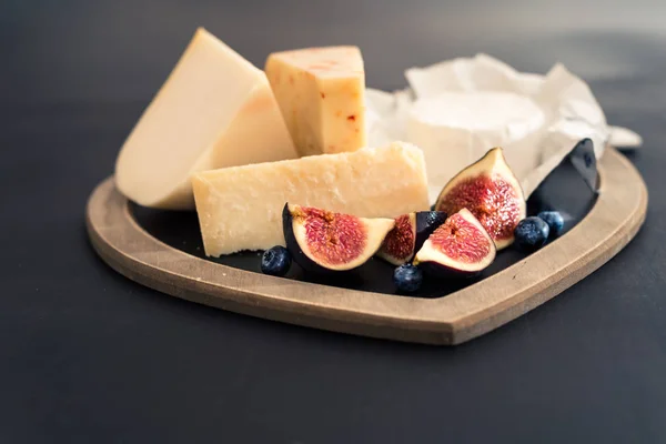 Olika typer av ost på rustika träbord, getost, chèvre, grana padana, fig, blåbär — Stockfoto