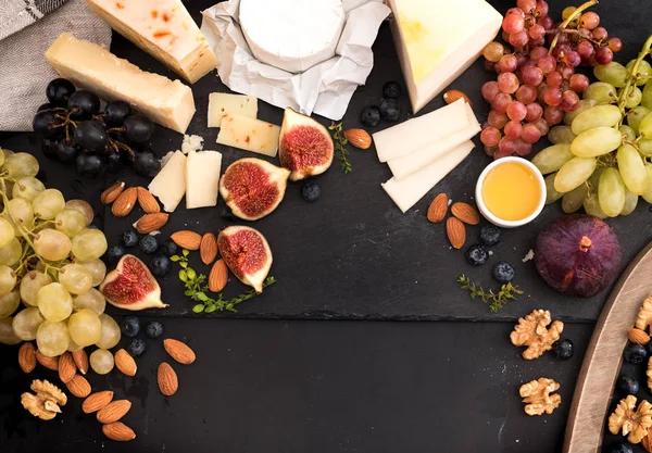 Provsmakning ostkupa med frukter, bär på gamla svart ostbricka. Mat för vin och romantiska, ost delikatesser. Menyn design horisontell. Ovanifrån. utrymme för text — Stockfoto