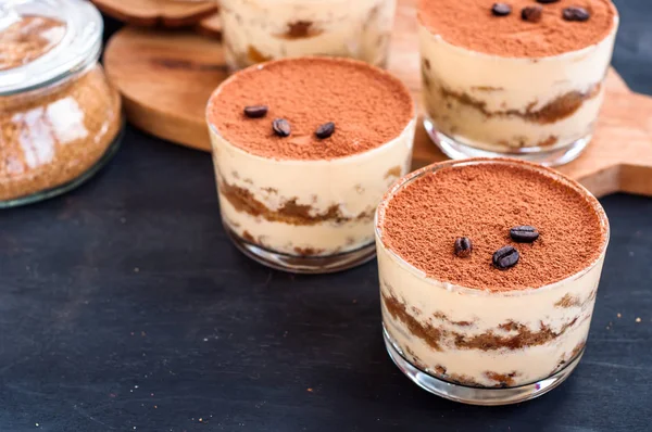Роскошный десерт Tiramisu в стакане с кофейными зернами на темном фоне — стоковое фото