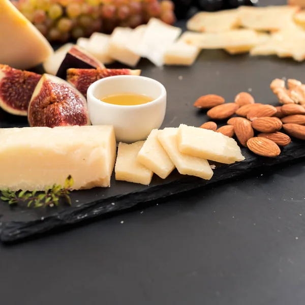 Honung skivad parmesan ost nutse frukt svart bakgrund — Stockfoto