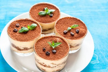 lüks tatlı Tiramisu mavi bir arka plan üzerine bir bardak nane ile dekore edilmiştir.