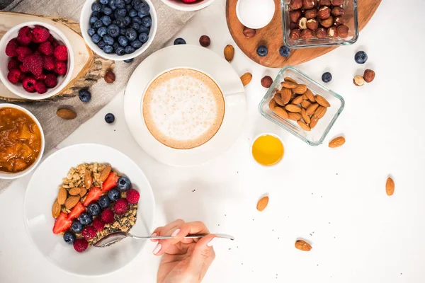 Günaydın - yulaf ezmesi kahve, çilek, yumurta, fındık ile sağlıklı kahvaltı arka plan. Kahve, eller, tutun, cup. Beyaz ahşap gıda arka plan, üstten görünüm
