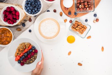 Günaydın - yulaf ezmesi kahve, çilek, yumurta, fındık ile sağlıklı kahvaltı arka plan. Kahve, eller, tutun, cup. Beyaz ahşap gıda arka plan, üstten görünüm