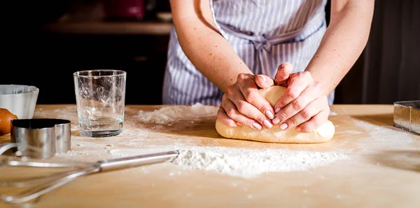 Le mani delle donne impastano l'impasto sul tavolo, accessori cucina — Foto Stock