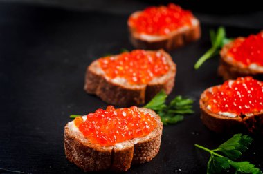 tereyağı ile siyah ekmek üzerinde kırmızı havyar. Sağlıklı gıda. Balık meze. koyu arka plan