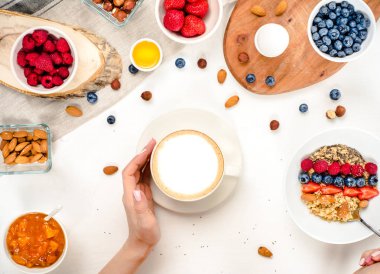 Günaydın - yulaf ezmesi kahve, çilek, yumurta, fındık ile sağlıklı kahvaltı arka plan. Kahve, eller, tutun, cup. Beyaz ahşap gıda arka plan, üstten görünüm