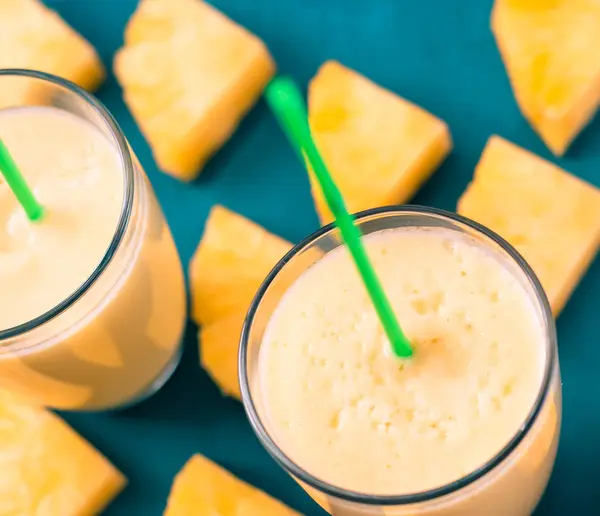 Batido de piña con piña fresca sobre mesa azul madera . — Foto de Stock