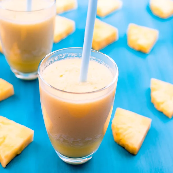 Piña en rodajas con un vaso de jugo de piña sobre un fondo de madera azul — Foto de Stock