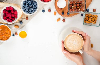 Günaydın - yulaf ezmesi kahve, çilek, yumurta, fındık ile sağlıklı kahvaltı arka plan. Kahve, eller, tutun, cup. Beyaz ahşap gıda arka plan, üstten görünüm