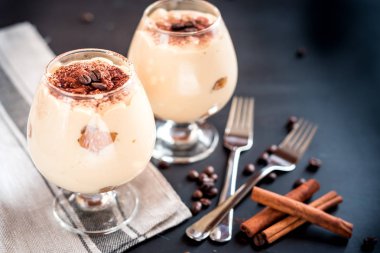 karanlık bir arka plan üzerinde kahve çekirdekleri ile dekore edilmiş bir cam tiramisu