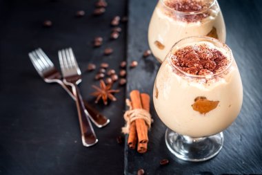 karanlık bir arka plan üzerinde kahve çekirdekleri ile dekore edilmiş bir cam tiramisu