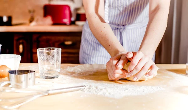 As mãos de mulher amassam a massa de farinha em uma mesa, para as férias — Fotografia de Stock