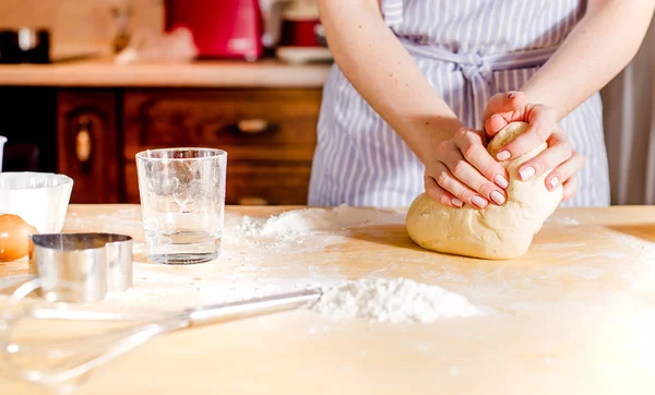 Le mani di donna impastano la pasta su un tavolo — Foto Stock