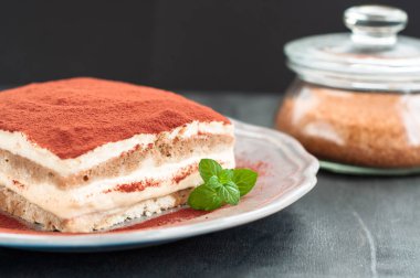 İtalyan tiramisu tatlı siyah bir zemin üzerine porselen tabakta