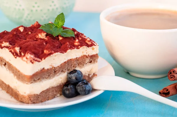 Dessert tiramisù italiano su un piatto di porcellana, su fondo blu — Foto Stock