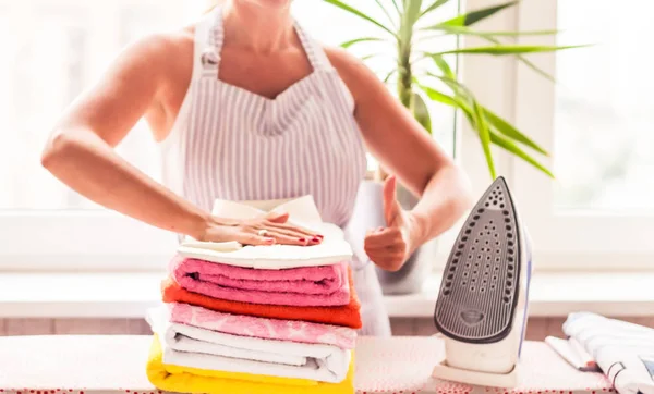 Ironing clothes on ironing board, ironed clothes ironing, laundry, clothes, housekeeping and objects concept - close up of ironed and folded shirts on table at home