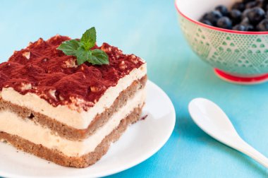 İtalyan tiramisu tatlı mavi bir arka plan üzerinde bir porselen tabak