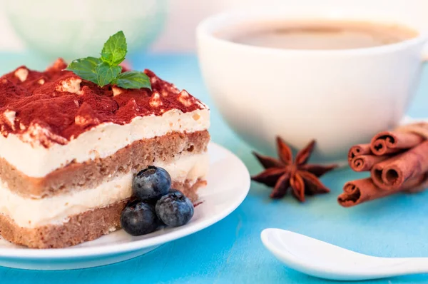 Italiaanse tiramisu dessert op een porseleinen plaat, op een blauwe achtergrond — Stockfoto