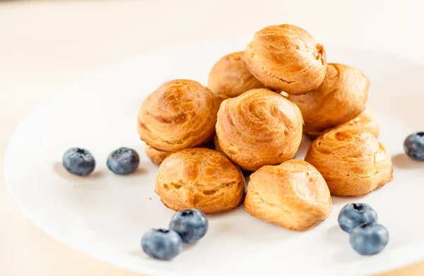 Profiteroles maison servis avec des bleuets sur une assiette blanche — Photo