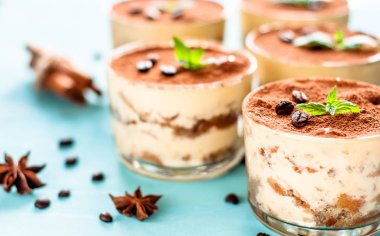 lüks tatlı Tiramisu mavi bir arka plan üzerine bir bardak nane ile dekore edilmiştir.