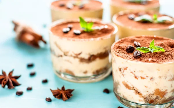 Luxurious dessert Tiramisu in a glass on a blue background decorated with mint — Stock Photo, Image