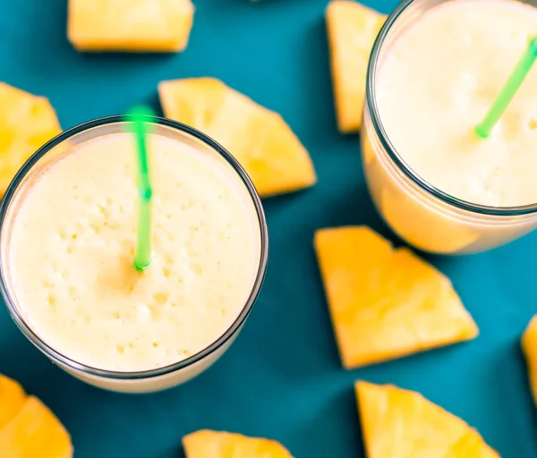 Piña en rodajas con un vaso de jugo de piña sobre un fondo de madera azul — Foto de Stock