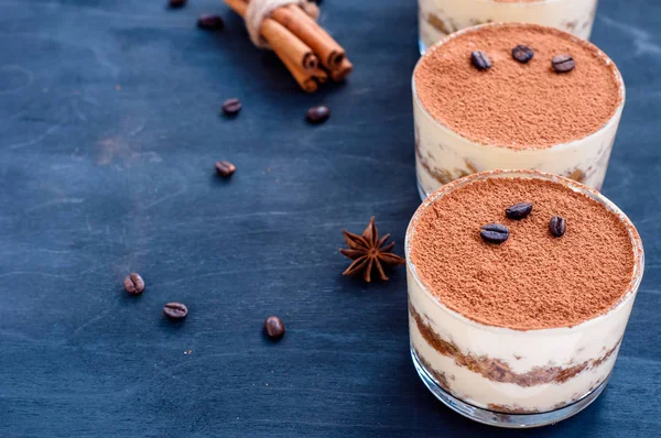 Tiramisu em um copo decorado com grãos de café em um fundo escuro — Fotografia de Stock