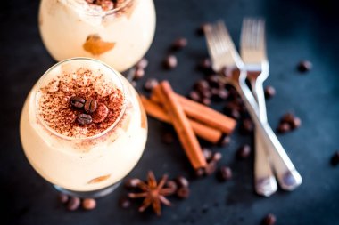 karanlık bir arka plan üzerinde kahve çekirdekleri ile dekore edilmiş bir cam tiramisu