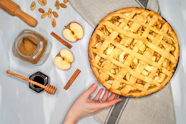 Tarte aux pommes sur un torchon gris. Mains sur la table. Pommes, cannelle, sucre, miel et noix, vue de dessus — Photo